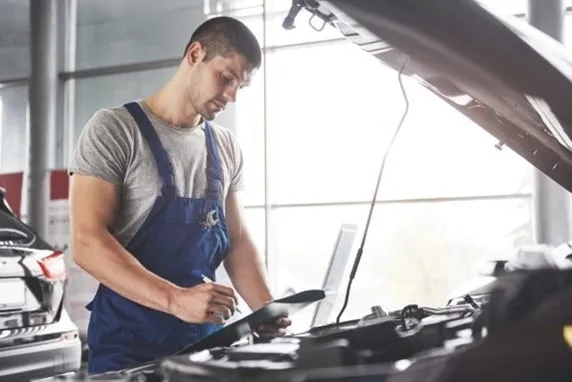 Profesionálna kontrola vozidla: technik starostlivo preveruje stav motora a zaznamenáva všetky zistenia.